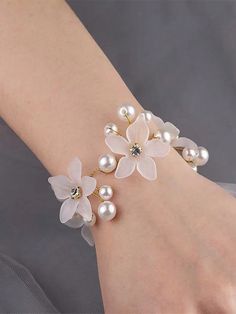 a close up of a person wearing a bracelet with flowers and pearls on the wrist