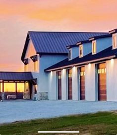 a large white house with two garages in front of it at sunset or dawn