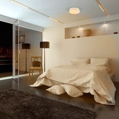 a white bed sitting in a bedroom on top of a hard wood floor next to a window