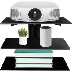 a white projector sitting on top of a shelf next to books and a potted plant