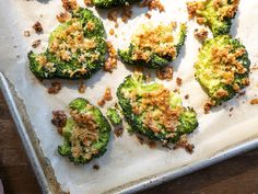 broccoli florets are on a baking sheet with some crumbs