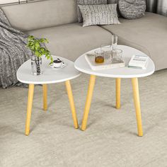 two white tables with yellow legs in front of a couch and coffee table next to each other