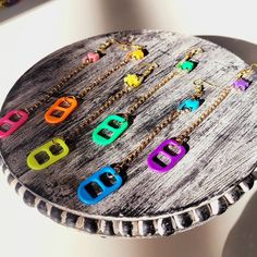 there are many different colored letters on this wooden tray that is decorated with gold chains