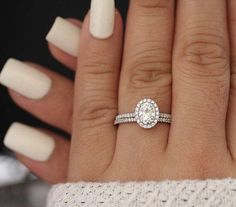 a woman's hand with white nails and a ring on her finger, holding a diamond