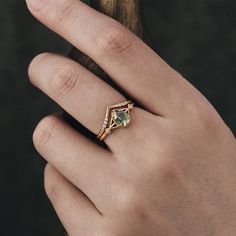 a woman's hand with a ring on it and a green stone in the middle