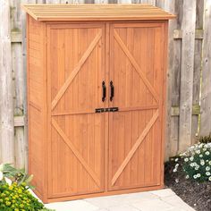 a wooden storage shed with two doors on the front and one door open to reveal a flower garden