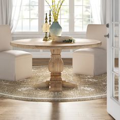 a dining room table with two chairs and a vase on it in front of a window