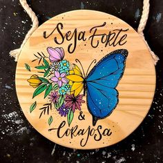 a wooden sign with a blue butterfly and flowers on it that says sega fotete & cragsa