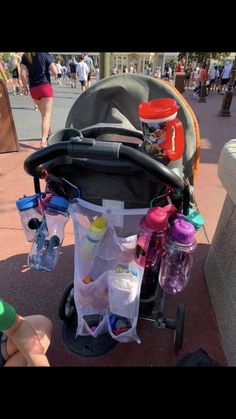 the stroller is full of baby bottles and diapers on the sidewalk in front of people