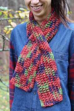 a smiling woman wearing a crocheted scarf in red, green, blue and purple