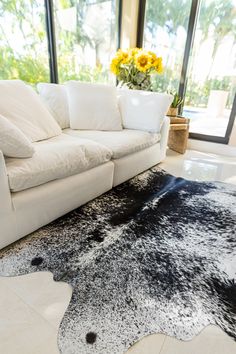 a living room with a white couch and black and white area rug on the floor