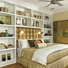 a bed sitting in a bedroom next to a book shelf filled with lots of books