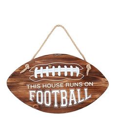 a wooden sign that says this house runs on football with a ball hanging from it