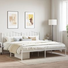 a white bed sitting in a bedroom on top of a hard wood floor next to a window