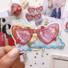 a person holding up a sticker with heart shaped glasses on it