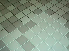 a white toilet sitting in a bathroom next to a tiled floor and walls with gray squares on it