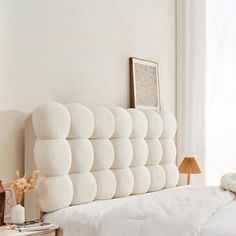 there is a white bed with pillows on the headboard and night stands next to it