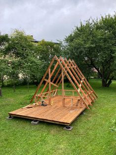 a wooden structure sitting on top of a lush green field