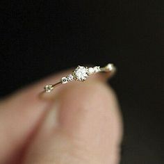 a person holding a tiny diamond ring in their hand