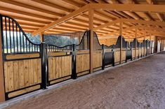 the inside of a horse barn with wooden stalls