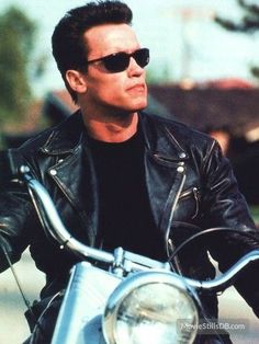 a man in black leather jacket and sunglasses on a motorcycle