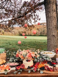 a table topped with lots of food next to a tree