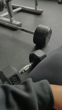 a person with their arm around a barbell on the ground in a gym area