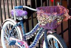 a purple bicycle with a basket on the front is parked in front of a gate