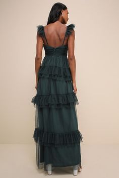 the back of a woman wearing a dark green dress with tiered layers and open shoulders