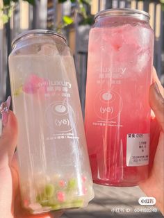 two people holding up plastic cups with drinks in them, one is pink and the other is green