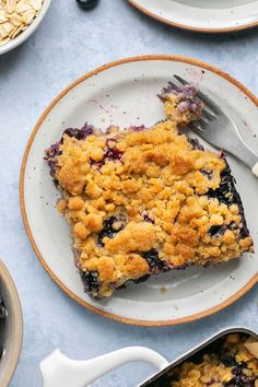 a piece of blueberry crumble cake on a plate with a fork next to it