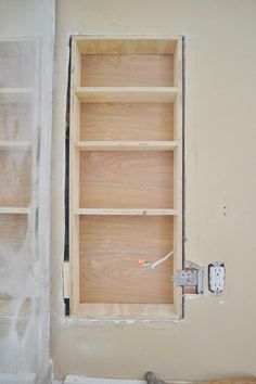 an empty room with unfinished shelves and a window in the wall that has been painted white