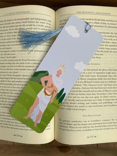 an open book with a paper cut out of it and a tassel on top