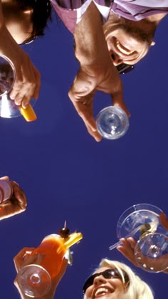 several people are holding drinks and looking up at the sky