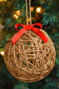 an ornament hanging from a christmas tree decorated with twine and red ribbon