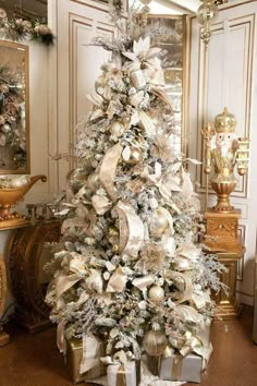 a decorated christmas tree in a room with gold and white decorations on the treestop