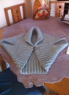 a knitted sweater sitting on top of a wooden table