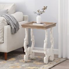 a white couch sitting next to a wooden table on top of a carpeted floor