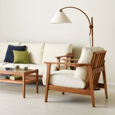 a living room filled with furniture and a lamp on top of a wooden table next to a white couch