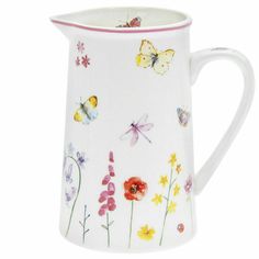 a white pitcher with colorful flowers and butterflies painted on the side, in front of a white background