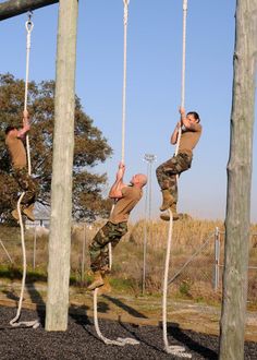 two men are hanging upside down on ropes