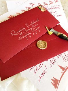 a red envelope with a wax stamp on it and a gold seal sitting next to it