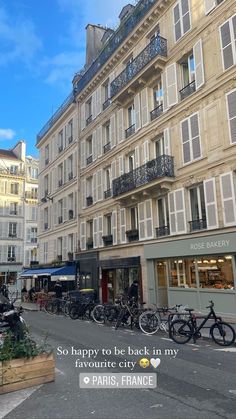 there are many bikes parked in front of the buildings on this street and people walking down the sidewalk