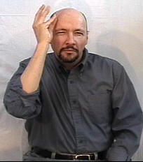 a man holding his hands up in the air while standing next to a white wall