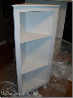 a white book shelf sitting on top of a hard wood floor