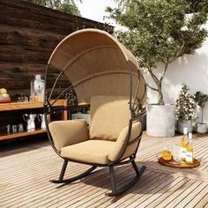 an outdoor swing chair sitting on top of a wooden deck next to a table and potted plants