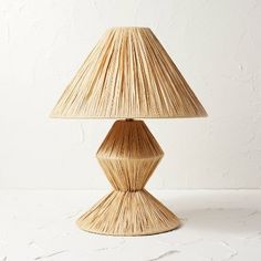 the lamp is made out of straw and has a large shade