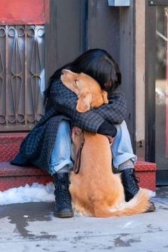 a woman sitting on the ground hugging her dog