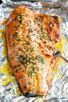 a piece of cooked salmon on tin foil with a fork in it and seasoning sprinkles