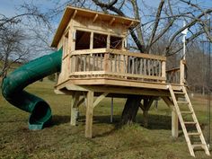 a tree house with a slide in the grass